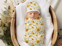 a baby sleeping in a basket with sunflowers on it