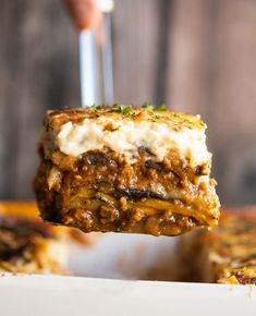 a piece of lasagna being lifted from a casserole dish with cheese