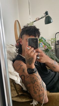 a man taking a selfie with his cell phone in front of him and tattoos on his arms