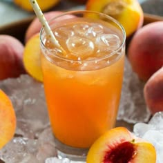 a glass filled with orange juice sitting on top of ice next to sliced peaches