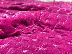 a bed covered in pink sheets with gold stars