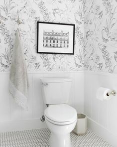 a white toilet sitting in a bathroom next to a towel rack and wall hanging above it