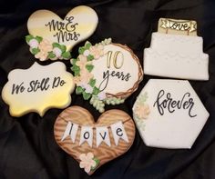 decorated cookies are arranged in the shape of hearts and flowers on a black cloth background