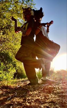 two people are dancing in the woods with their arms around each other and one person is holding something