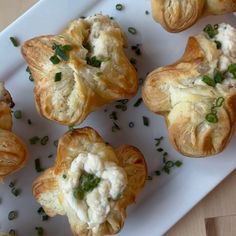 small pastries are on a white plate with green garnishes and sprinkles