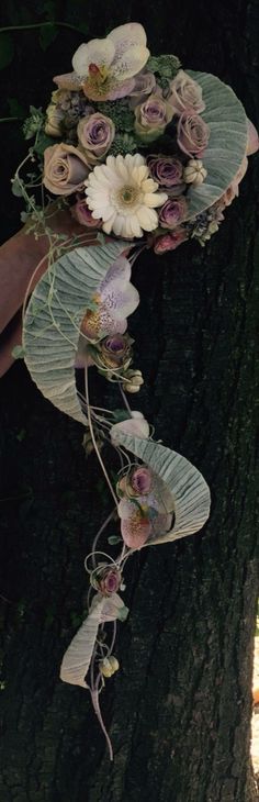 a bouquet of flowers is attached to a tree trunk with vines and leaves on it