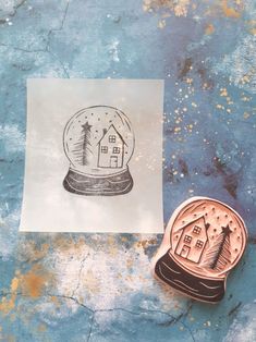 a stamp with a snow globe on it next to a piece of paper that has a house inside