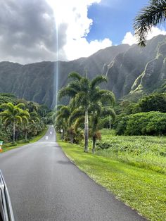 there is a car driving down the road with mountains in the backgrouds