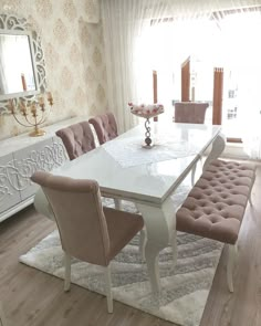 a dining room table with chairs and a bench in front of a mirror on the wall