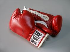 a pair of red boxing gloves sitting on top of a gray table with writing on it