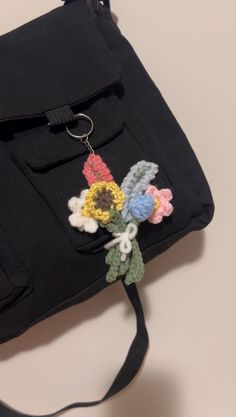 a black bag with flowers attached to the side and a keychain hanging from it