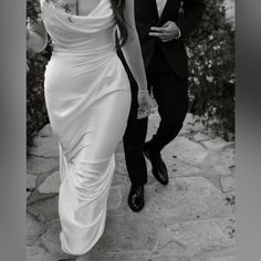 a woman in a white dress walking next to a man in a tuxedo