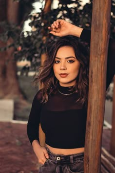 a woman standing next to a wooden pole