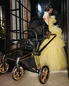 a woman in a yellow dress standing next to a stroller