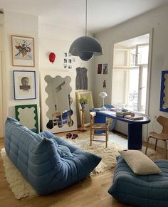 a living room filled with blue furniture and pictures on the wall above it's windows