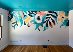 an empty room with painted flowers on the wall and wood flooring in front of it