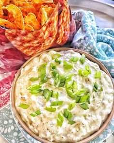 a bowl of dip and some chips on a plate with a cloth next to it