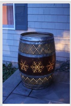 a wine barrel with snowflakes on it sitting in front of a house at night