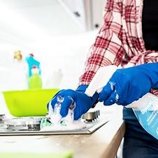 a person in blue gloves is cleaning a kitchen counter with a sponge and detergent