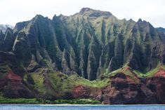 the mountains are covered in green grass and brown rocks, along with blue water on either side