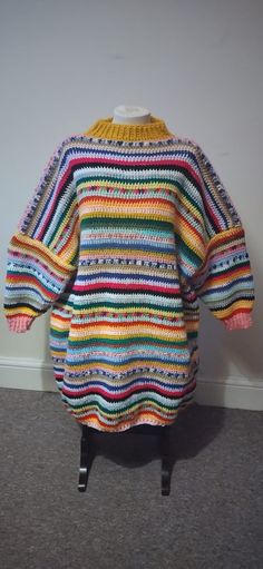 a multicolored sweater is hanging on a clothes rack in a room with carpeting