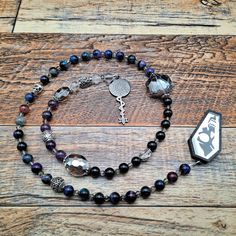 a beaded necklace with charms and a pendant on it sitting on a wooden surface