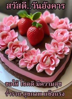 a heart shaped cake with pink flowers and two strawberries on top is shown in thai