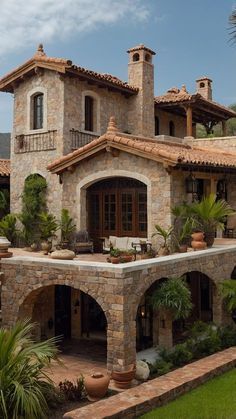 a large stone house with lots of plants and trees in front of the house is surrounded by greenery