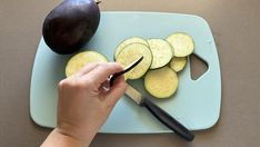 a person cutting up some food on a blue plate with a knife and an eggplant