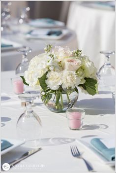 a vase filled with white flowers sitting on top of a table next to silverware