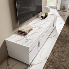 a tv stand with a book on top of it next to a wall mounted television