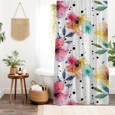 a shower curtain with colorful flowers on it next to a bathtub and potted plant