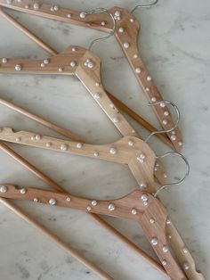 four wooden clothes hangers with white pearls on the ends and one is made out of wood