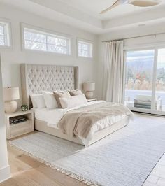 a bedroom with a large bed and white furniture in front of a sliding glass door