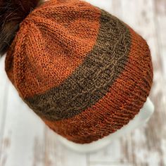 an orange and brown hat with a fur pom