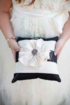 a woman is holding a black and white clutch bag with a flower on it's side