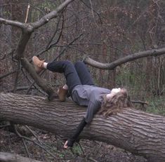 a woman laying on top of a fallen tree