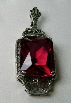 "Simulated Red Ruby Pendant Lantern Design#P13 Custom Made About 6 months ago I found a lovely Art Deco brooch and fell in love with the design. Fashioned in the design of the brooch, I now offer this lovely Antique reproduction pendant in sterling silver (matching 18ct earrings also available for sale). The flawless Simulated 9ct red/pink ruby is 15mm long (just over 9/16\") and 12mm in width (1/2th\"). The pendant is 1 3/8th inches long, it is 9/16th\" wide. The bail opening is 3.5mm wide and Silver Lanterns, Pendant Lantern, Mystic Fire Topaz, Art Deco Brooch, Pink Ruby, Filigree Necklaces, Lantern Design, 1930s Art, Ruby Pendant