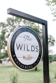 a sign for the wilds at gathering place in front of some grass and trees