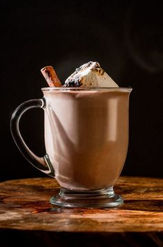 a cup filled with hot chocolate and marshmallows on top of a wooden table