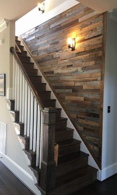 a wooden stair case next to a light on the wall