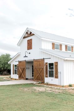 a large white barn with wooden doors and windows