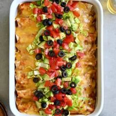 an enchilada dish with black olives, tomatoes and lettuce