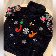 a black sweater with snowflakes and letters on it