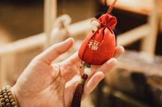 a person holding a small red bag with writing on it and a tassel in their hand