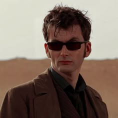 a man wearing sunglasses and a jacket in the desert