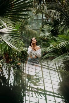 a woman is talking on her cell phone while standing in the middle of palm trees