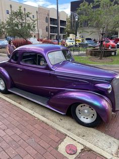 an old purple car is parked on the side of the road