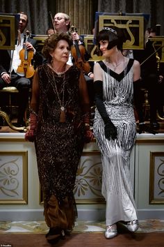 two women standing next to each other with musical instruments in the background