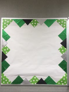 a piece of white paper with green and black squares on it, sitting in front of a gray wall